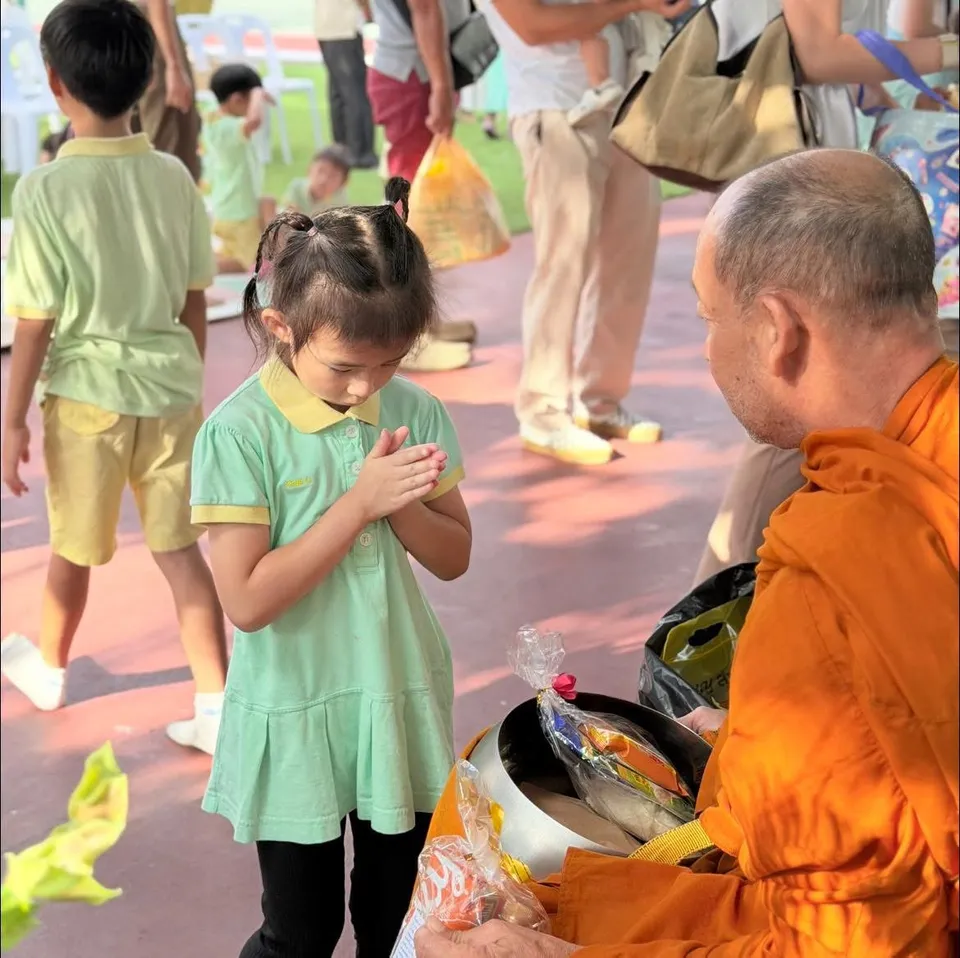 A girl in school uniform makes a respectful wai to a monk